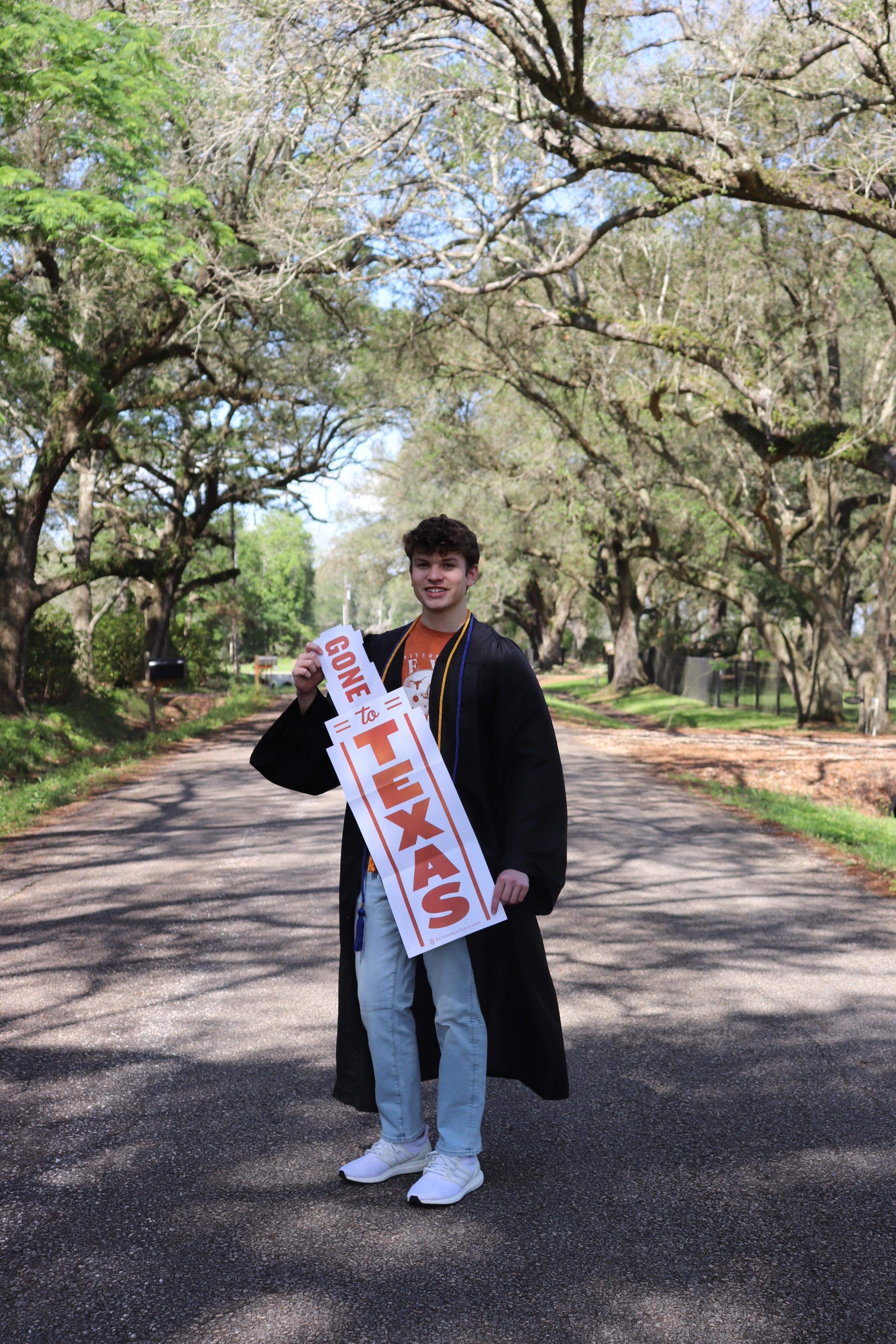 Sterling standing outdoors holding a University of Texas sign